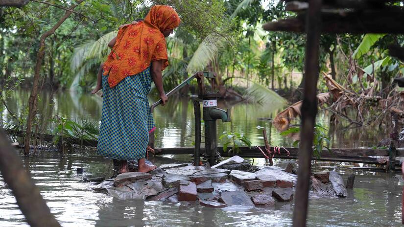 Even when surrounded by floodwaters, people often lack access to clean, drinkable water. This woman has waded to a water pump provided by the IFRC and the Bangladesh Red Crescent.
