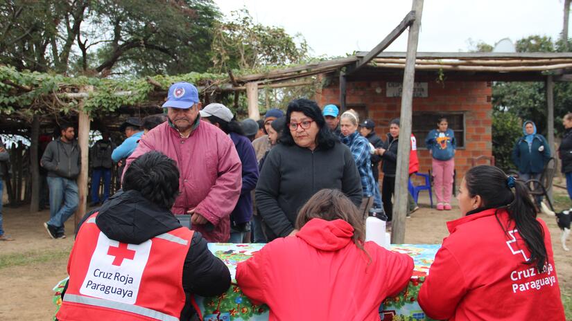 Tres personas de la Cruz Roja Paraguaya registran a las personas afectadas por las fuertes lluvias de abril y junio en Ñeembucú, para luego brindarles ayuda humanitaria de acuerdo a sus necesidades.