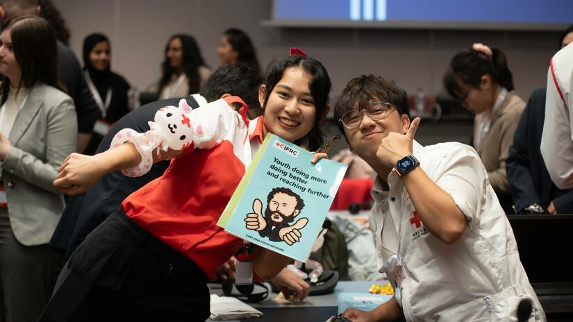 Volunteers attending the IFRC Youth Forum give a thumbs up as they hold up an IFRC document on youth participation.