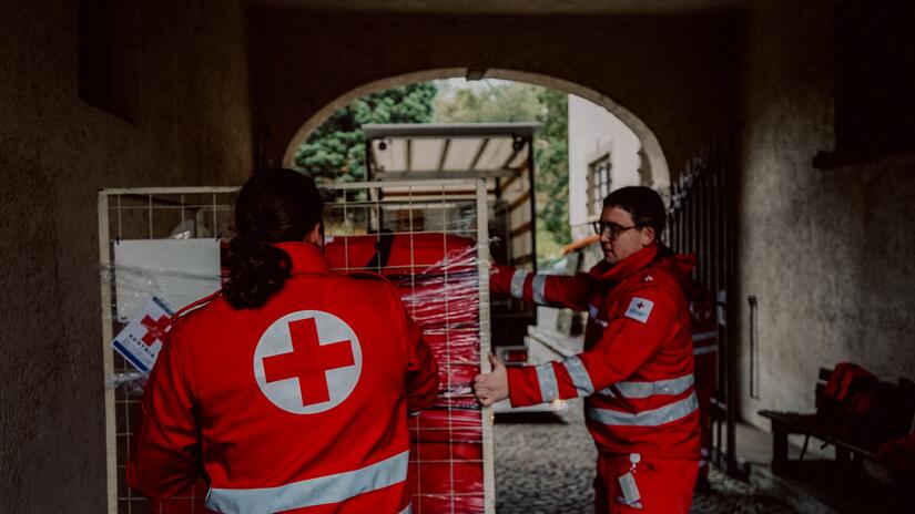 Volunteers with the Austrian Red Cross prepare supplies to be loaded on a truck for distribution.