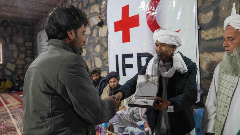 An IFRC staff member hands over the keys of a newly constructed shelter to one of the families impacted by the October 2023 earthquakes during a shelter handover ceremony in November.