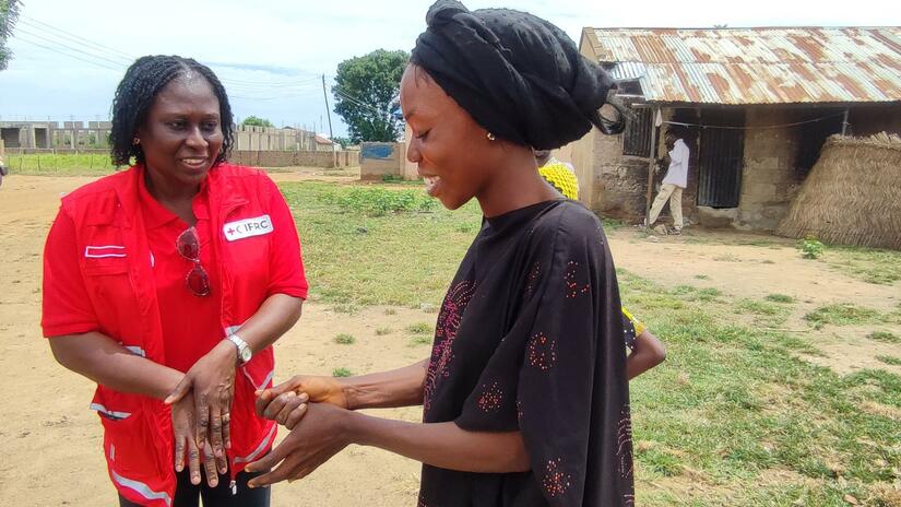 An IFRC Program Officer for the Reach Initiative, Lilian Adeogba, guides a community health worker in the essential practice of handwashing, ensuring health and safety for all.