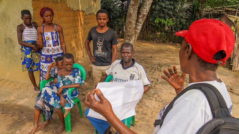 A DRC Red Cross volunteer with the CP3 programme speaks to a family about mpox symptoms, risks and infection prevention methods in July 2024.