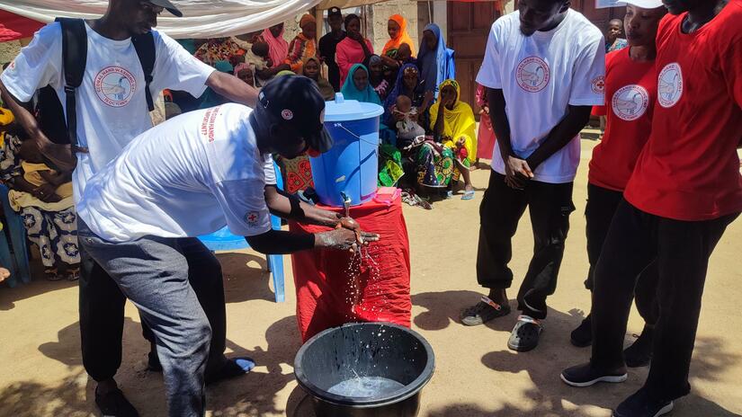 Nigerian Red Cross Society volunteers training people in the Fufore community in Adamawa state, Nigeria, on the life-saving practice of handwashing.