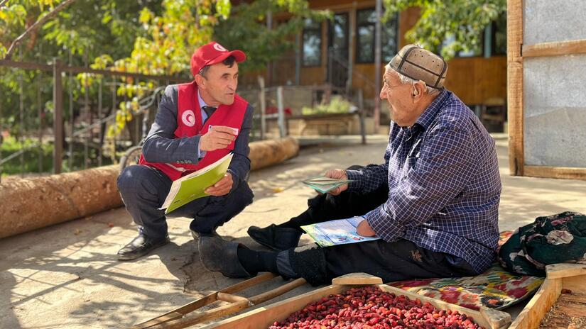أحد متطوعي الهلال الأحمر الطاجيكستاني في منطقة "مولامير" النائية يتحدث إلى أحد أصحاب الماشية عن خطر الإصابة بالأمراض الحيوانية المنشأ، ويشرح له كيف يمكنه التعرف على علامات المرض في أبقاره والإبلاغ عنها.