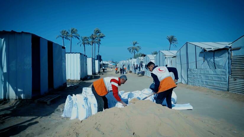Palestine Red Crescent volunteers fill sacks with sand at a camp for displaced people in Az Zawayda as part of efforts to protect the camp from flooding caused by recent rains.