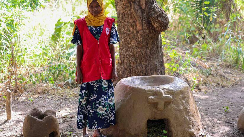 Mothers’ Club Member, Alima Abubakar from the Oumalo Community in northern Togo, stands by one of the earthen stoves made to reduce the amount of coal and firewood used in cooking.