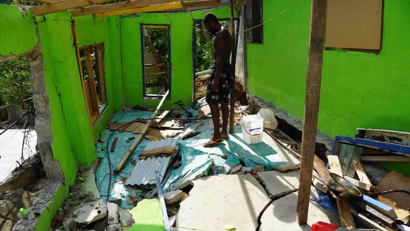 A man stands inside what's left of his home following the December 17 earthquake and its many aftershocks.