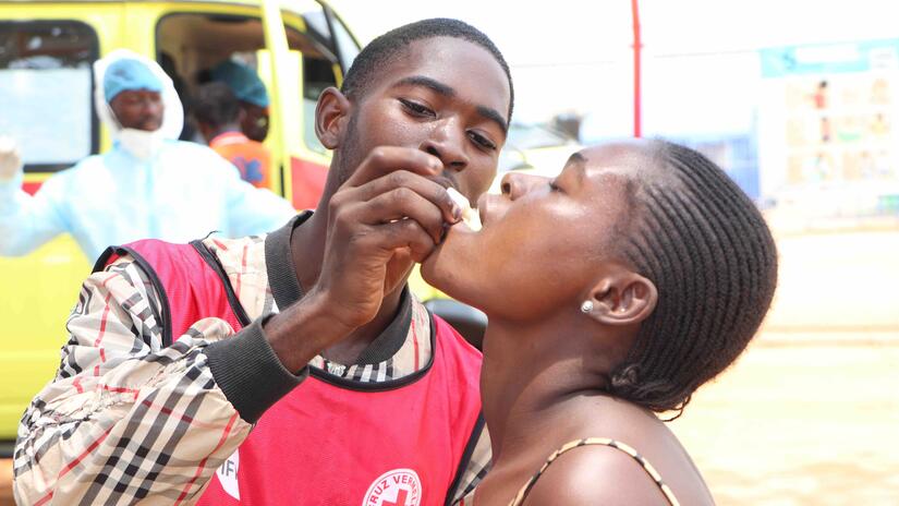 A volunteer with the Angola Red Cross provides an oral cholera vaccine during a community outreach in Luanda Province.