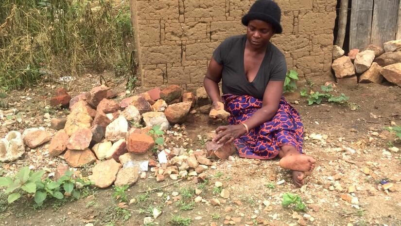Sitting on the ground near her home, 49-year-old Patricia crushes stones that are then sold to people for use in building projects. This is one of several ways she supports her family.