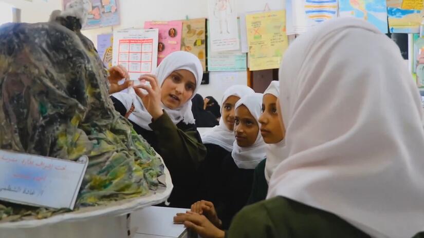 تشرح أليف مشروعها العلمي لطالبات أخريات في مدرسة أسماء للبنات.