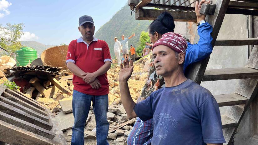 A volunteer with the Nepal Red Cross listens as a local husband and wife, named Bohd and Binda, explain how they tragically lost their 12-year-old eldest son in last year’s flash flood.