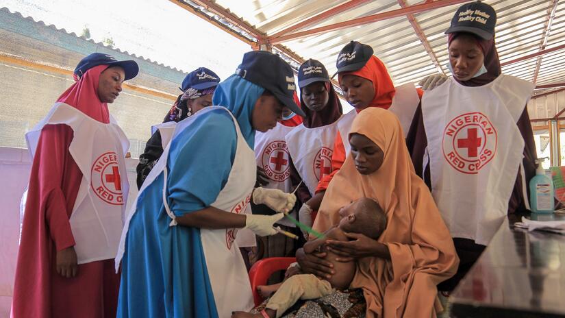 Nigerian Red Cross volunteers provide care to a child suffering from acute malnutrition.
