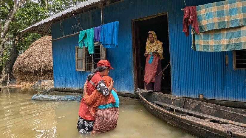  A volunteer from the Bangladesh Red Crescent Society (BDRCS) comforts a woman whose home has been inundated by floodwaters.