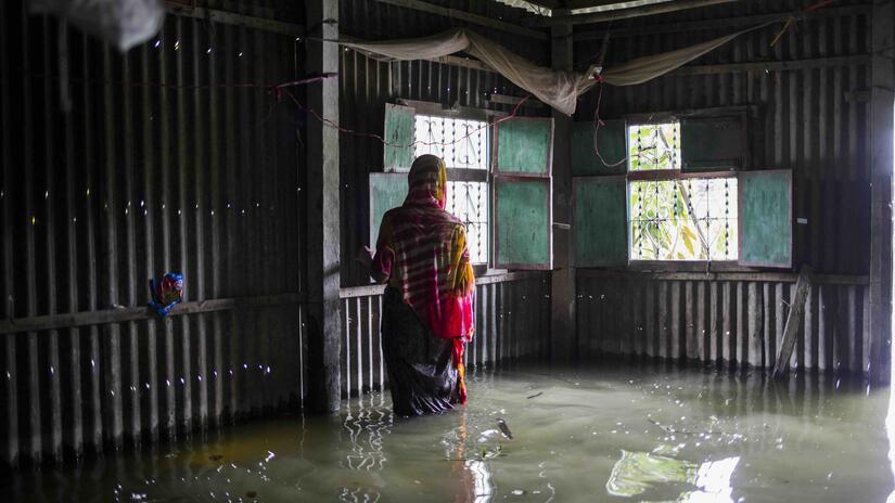 Jorina Begum, 60, checks her flood-damaged home in Sirajganj, Bangladesh, after severe 2020 floods forced her family to shelter by the roadside for two months.