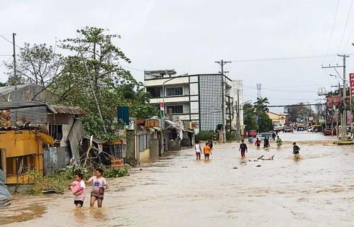 Peoplein Kabankalan City, Philippines wade through a flooded street after Typhoon Odette slammed into the coastal areas of Eastern Philippines on 16 December 2021 causing landslides and widespread flooding.