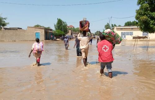 Chad Red Cross volunteers help flood-affected communities carry their possessions through flood water.