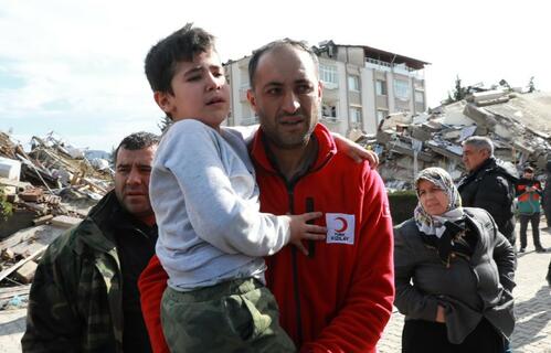 A Turkish Red Crescent volunteer carries a young boy away from the rubble of a collapsed building following two deadly earthquakes n 6 February 2023.