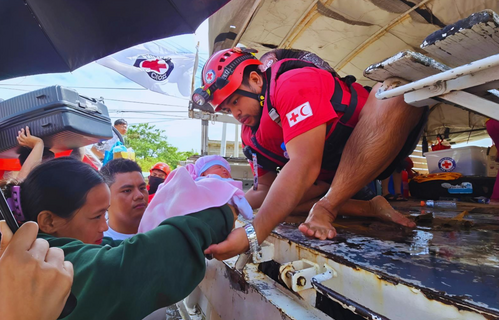 People gather to receive aid packages from the IFRC and Philippines Red Cross after Cyclone Kristine