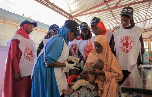 Nigerian Red Cross volunteers provide care to a child suffering from acute malnutrition.
