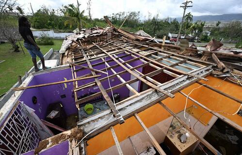 A man stands on what is left of the roof of his neighbour following the passage of Hurricane Melissa, in Longwood, St Elizabeth, Jamaica on October 29, 2025. 