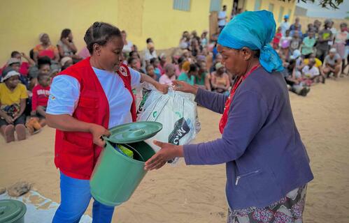 A Mozambique Red Cross volunteer provides critical supplies to a woman impacted by heavy flooding.