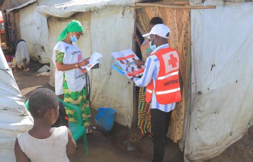 A DRC Red Cross volunteer shares an educational leaflet and talks with a community member about Ebola prevention. Supported by the IFRC, volunteers are going door-to-door to combat misinformation and encourage early medical care.