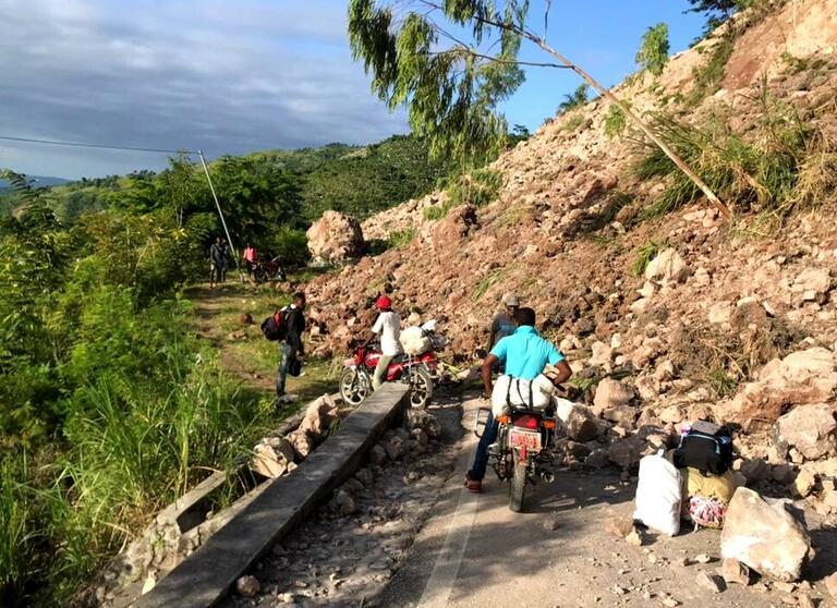 People in Haiti evacuate while navigating landslides caused by the earthquake.