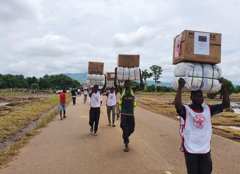 Malawi Red Cross volunteers carry relief supplies on their heads to reach people living in camps who were affected and displaced by Tropical Storm Ana in January 2022.