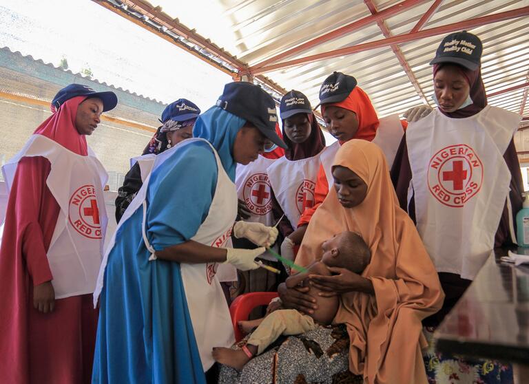 Nigerian Red Cross volunteers provide care to a child suffering from acute malnutrition.