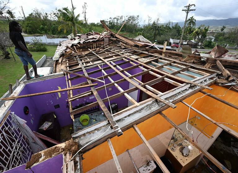 A man stands on what is left of the roof of his neighbour following the passage of Hurricane Melissa, in Longwood, St Elizabeth, Jamaica on October 29, 2025. 