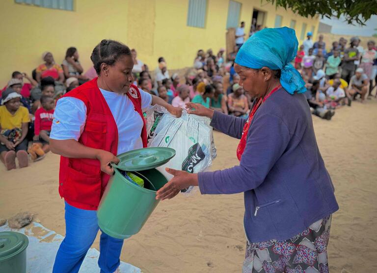 A Mozambique Red Cross volunteer provides critical supplies to a woman impacted by heavy flooding.