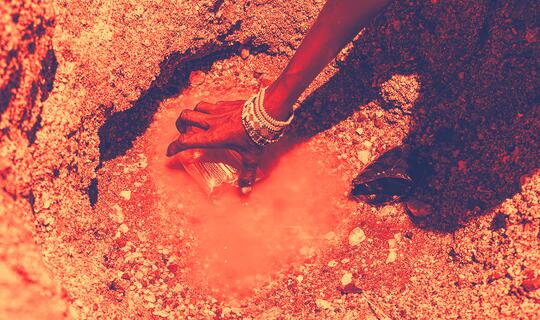 A woman collects water from a shrinking water hole in drought-impacted area of northeastern Kenya.