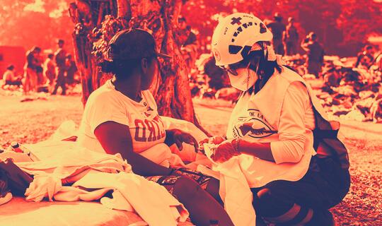 A Venezuelan Red Cross volunteer provides first aid to a woman affected by the June 24 earthquakes in Venezuela.