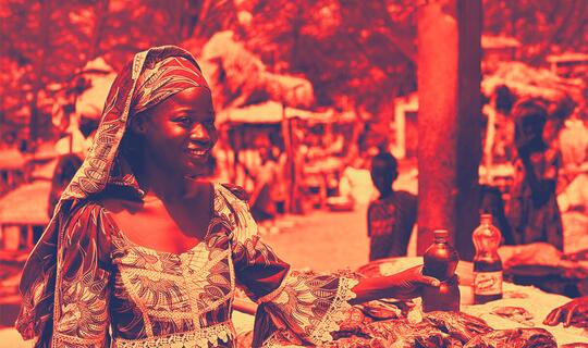 Fatimatou stands in front of a market stall where she will buy essential goods. She has just received cash assistance through the Cameroon Food Insecurity Emergency Appeal.