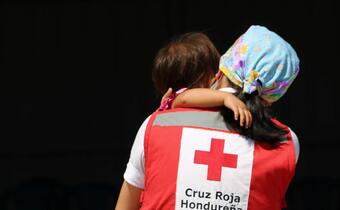 A Honduran Red Cross volunteer carries a small child rescued as part of their response to Hurricane Eta in 2020 which affected millions of people in the region