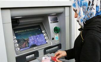 A woman withdraws money, which she receives as part of a large cash assistance programme in Turkey, from an ATM machine.