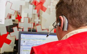 A Red Cross volunteer works in their office on a computer