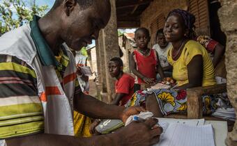 A volunteer with the Red Cross Society of Guinea addresses a family in the village of Klalantou in the Ebola hit region of Forecariah in Guinea during door-to-door sensitisation and surveillance activities aimed at preventing the spread of Ebola.