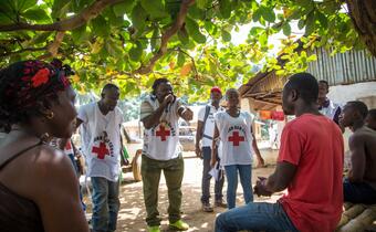 Red Cross volunteers discuss Ebola-related issues in a village on the Sierra Leone-Liberia border to help prevent the spread of disease and challenge harmful stigma.