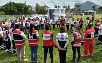 Mexican Red Cross and American Red Cross volunteers stand in a circle and discuss their joint response to the Puebla earthquake in 2018