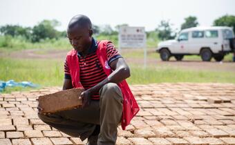 A shelter officer from the Nigerian Red Cross holds a brick made by trained community members in north east Nigeria