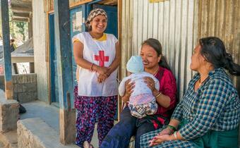 A volunteer with the Nepal Red Cross visits a new mother in Kaule, Nepal, an area heavily affected by the 2015 earthquake, to accompany her and her 5-month-old son to an immunisation appointment