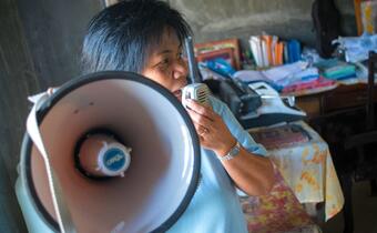 A Philippine Red Cross volunteer uses a megaphone to share safety messages with people in her community on Panay island when Typhoon Haiyan hit the country in 2013