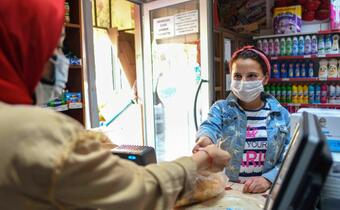 A young Syrian girl buys food supplies near her new home in Turkey with cash assistance received as part of the IFRC and Turkish Red Crescent's Emergency Social Safety Net (ESSN) project, funded by the European Union