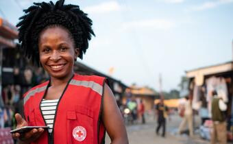 A Ugandan Red Cross volunteer encourages her community to attend a mobile cinema event where they can learn more about Ebola and how to protect themselves and their families