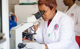 A medical worker from the Zimbabwe Red Cross looks through a microscope