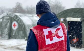 A red cross volunteer walks through a temporary camp in Lipa, Bosnia and Herzegovina set up to provide warm shelter, food and first aid to thousands of migrants stranded in freezing conditions