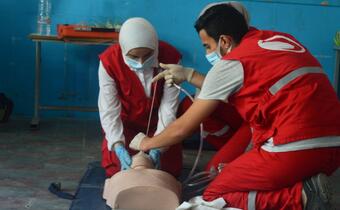 Tunisian Red Crescent volunteers practice performing CPR on a dummy as part of a first aid training course