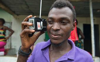 A man listens to a Red Cross broadcast on a cranking radio donated by the Sierra Leone Red Cross Society.